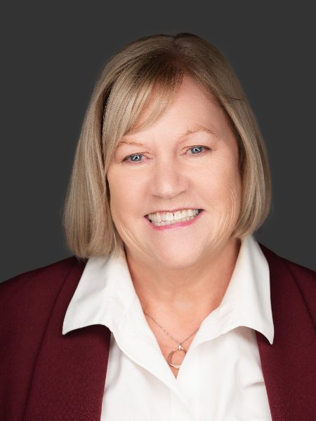 Laura Thurnheer smiling in a burgundy blazer and white collared shirt against a dark grey background