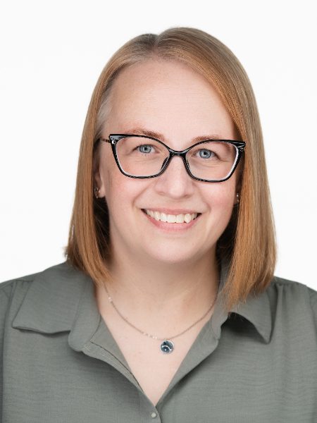Val Johnson smiling in glasses and an olive green blouse against a white background