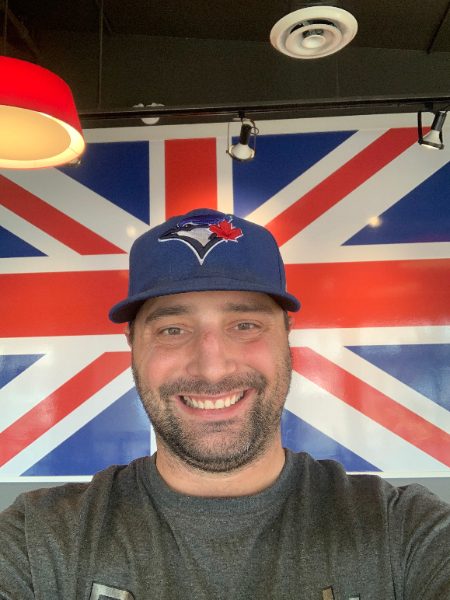 King James III taking a selfie in a Toronto Blue Jays cap in front of a Union Jack mural